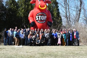 Union members posing for a group photo in front of a 20' red inflatable bull that says Stop Workplace Bullying